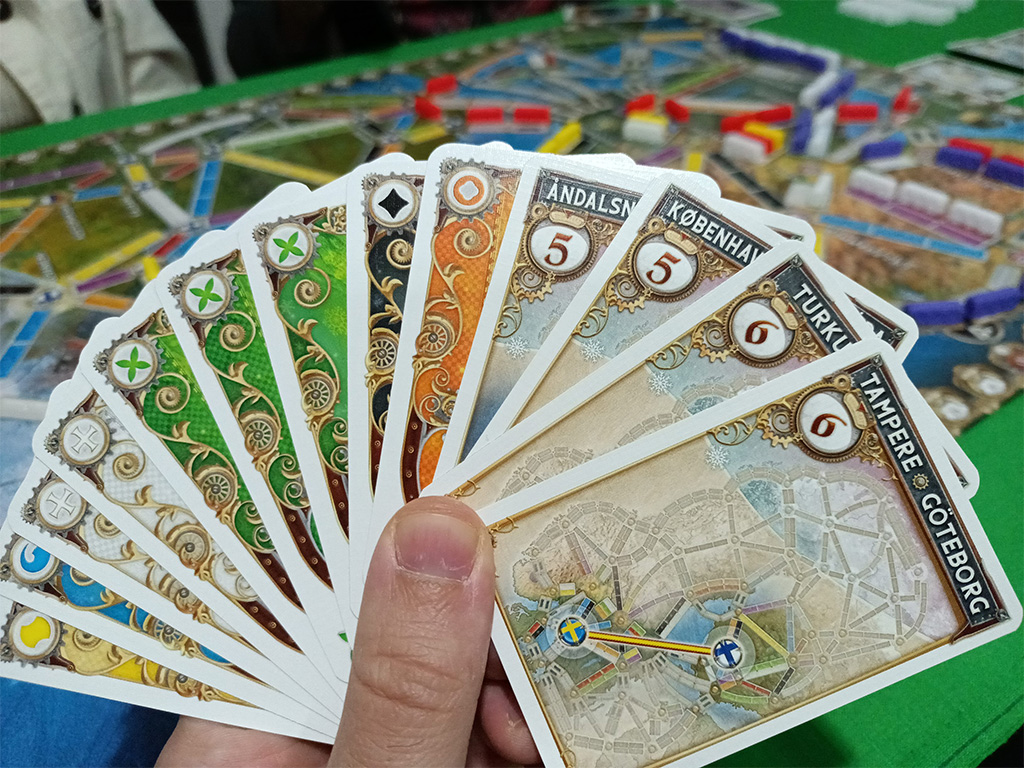 Per chi fosse proprio estraneo alle meccaniche di Ticket to Ride, vi invitiamo in primis ad approfondire gli altri titoli da noi recensiti. In secondo luogo, sappiate che per prendere possesso di una linea ferroviaria è necessario scartare dalla propria mano un numero di carte dello stesso colore della linea pari al numero di caselle che la compongono. Una volta ottenuta la linea, la si occupa con i propri vagoni e si guadagnano punti in base alla sua lunghezza. Per completare i Biglietti Destinazione, invece, dovrete assicurarvi che le due città indicate siano collegate da linee del vostro colore, indipendentemente dal percorso seguito.