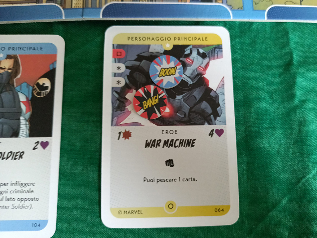 Una carta di Marvel: Skirmish! In New York. In alto a sinistra è visibile il numero e il colore di carte da scartare per poterla giocare. Le carte con l’asterisco grigio rappresentano una carta a libera scelta del giocatore.Il giocatore con gli Eroi può anche scartare i cubetti Civile in proprio possesso in sostituzione delle carte (vi spieghiamo a breve di cosa si tratta).